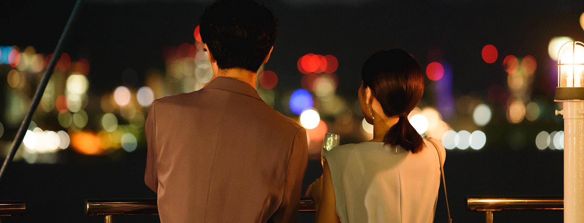 船上から神戸の夜景を眺めるカップル